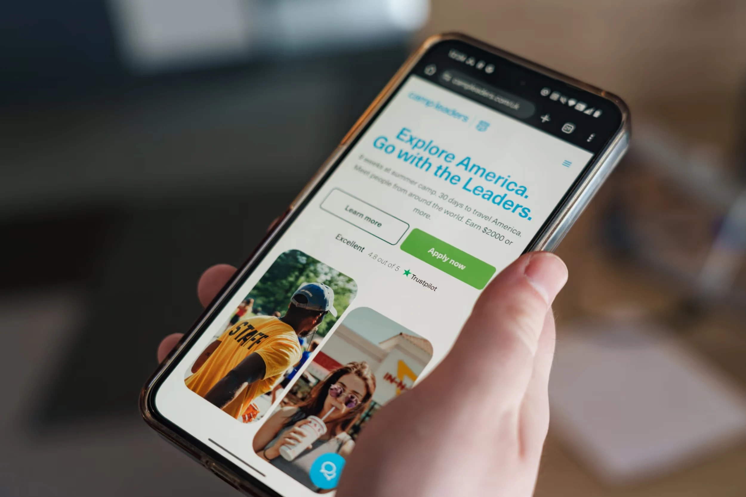A phone showing a camp website in someone's hand