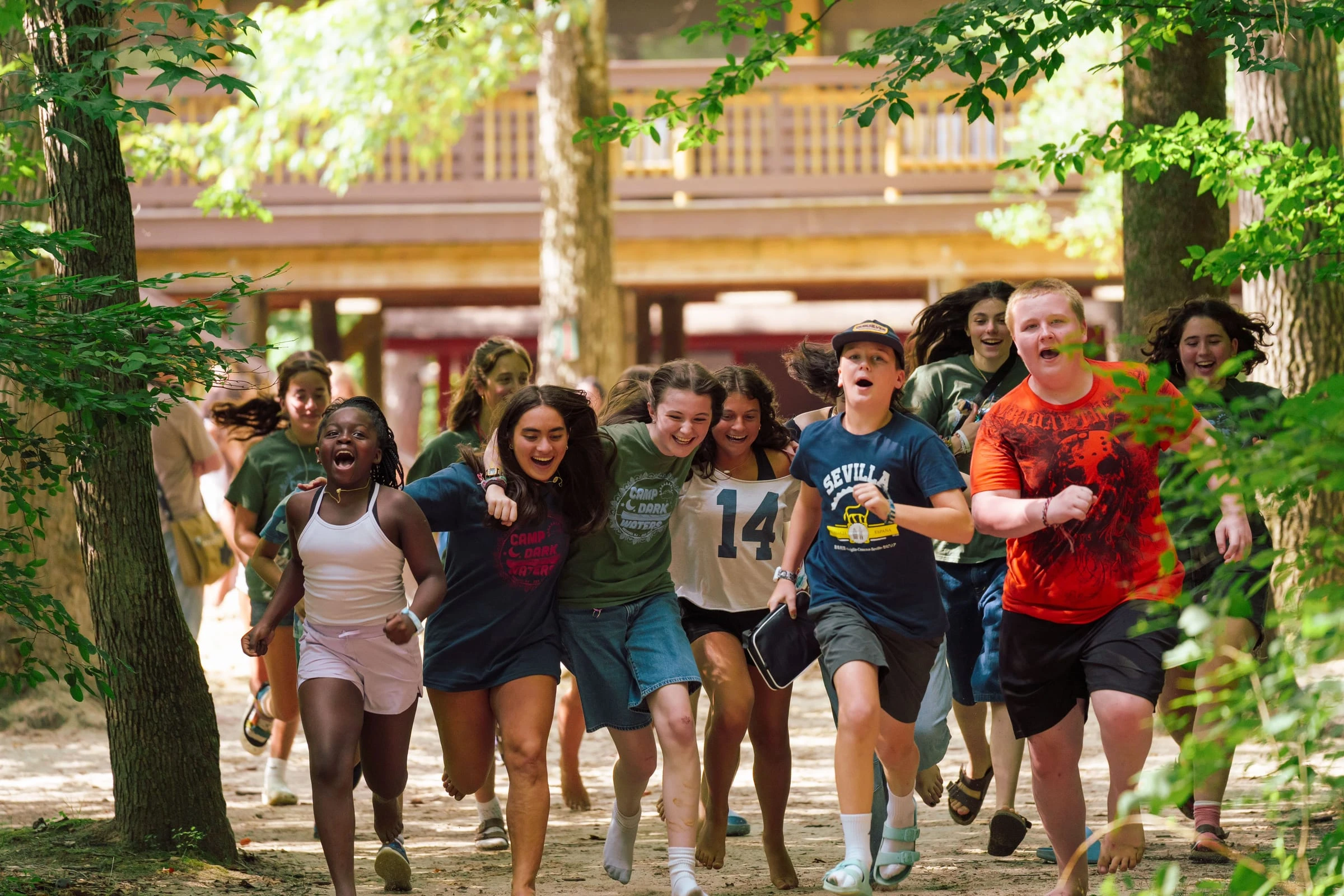 Campers running and laughing through the woods at summer camp